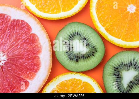 Sfondo di frutta fresca, motivo colorato di agrumi. Fetta di kiwi, arancio e pompelmo su sfondo luminoso. Primo piano con frutta esotica tropicale Foto Stock