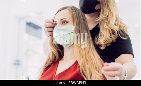 Donna con capelli freschi styling in negozio di tagliacapelli con maschera Foto Stock