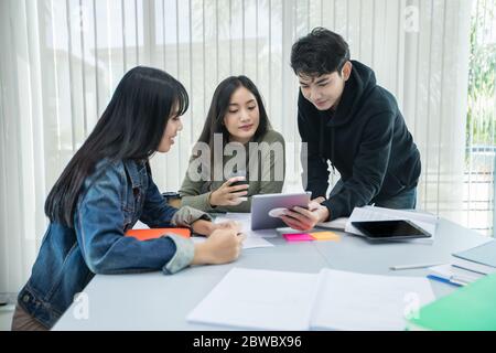 Gli studenti asiatici leggono libri e utilizzano tablet digitali per trovare informazioni per il lavoro e studi online Foto Stock