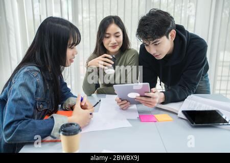 Gli studenti asiatici leggono libri e utilizzano tablet digitali per trovare informazioni per il lavoro e studi online Foto Stock