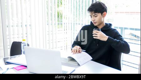 Gli studenti asiatici leggono libri e usano il notebook per trovare informazioni per il lavoro e gli studi online. Foto Stock