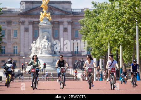 I ciclisti percorrono il Mall, mentre le persone godono del bel tempo a Londra, come si ricorda al pubblico di praticare la presa di posizione sociale a seguito del relax di restrizioni di blocco. Foto Stock