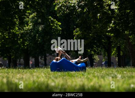 Amburgo, Germania. 31 maggio 2020. Una donna si trova in un parco al sole su un prato e legge un libro. Credit: Daniel Bockwoldt/dpa/Alamy Live News Foto Stock