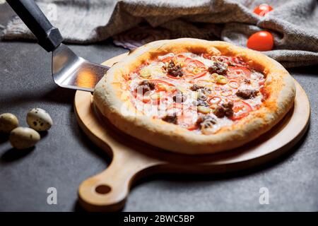 Pizza con pancetta, pomodori, formaggio e olive. Cucina italiana. Foto Stock