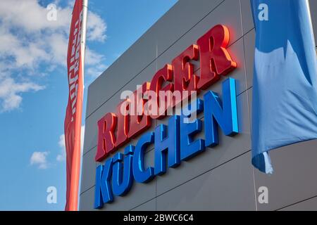 Göppingen, Germania - 21 maggio 2020: Cucine Rieger facciata, lettere blu e rosse, bandiera colorata, molta luce del giorno con cielo blu nuvoloso. Goeppingen. Foto Stock