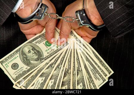 Manager mit Dollar Geldscheinen in der Hand, Hanschellen, verhaftet, Schwarzgeld,