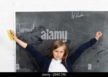 Lo studente, mentre strofinava la lavagna, sollevò le mani e si girò verso gli studenti in classe Foto Stock