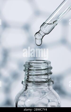 Goccia di olio sullo sfondo delle cellule biologiche. Pipetta cosmetica con Essence. Foto Stock