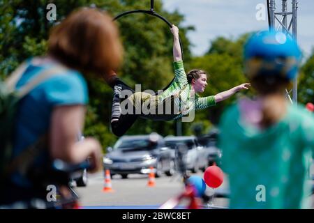 Mannheim, Germania. 31 maggio 2020. I ciclisti guardano un artista di trapezio che esegue trucchi in un drive-in circense del circo dei bambini e dei giovani 'Paletti'. Secondo gli organizzatori, un ampio parcheggio a Mannheim sarà il primo drive-in circense in Germania. Le famiglie passeranno varie attrazioni nelle loro auto mentre attraversano la 'terra del circo', caratterizzata da clown, giocolieri, uniciclisti, camminatori a trompe e artisti del trapezio. Credit: Uwe Anspach/dpa/Alamy Live News Foto Stock