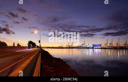 Vista in lontananza della facciata esterna sull'acqua al tramonto. Terminal delle navi da crociera Royal Caribbean Miami, Miami, Stati Uniti. Architetto: Broadway Malyan li Foto Stock