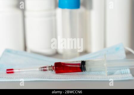Compresse in vasetti, gel antisettico, maschera monouso, siringa con vaccino rosso sviluppo di un vaccino contro Covid-19 da parte degli scienziati Foto Stock