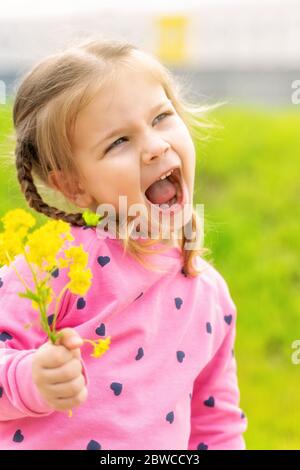 bambina con fiori gialli in una giornata di sole, retroilluminazione Foto Stock