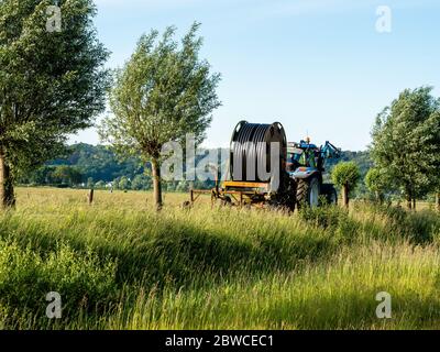 Zona di Nijmegen, Paesi Bassi. 31 maggio 2020. Un trattore trasporta un impianto sprinkler da utilizzare sul campo.nei Paesi Bassi si sta verificando la molla più secca mai registrata. È più secca che nel 2011, finora, questa primavera è quella con il più grande deficit di precipitazioni. A causa della siccità persistente, gli agricoltori utilizzano impianti sprinkler per irrigare i loro campi. Dopo un inizio bagnato quest'anno, non è caduta molta pioggia da marzo. Gli effetti della siccità sono più evidenti nei Paesi Bassi orientali e meridionali, in particolare in agricoltura e natura. Credit: SOPA Images Limited/Alamy Live News Foto Stock