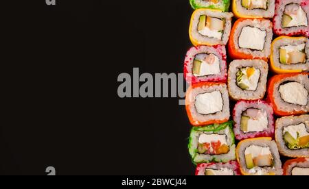 Panini di sushi in stile californiano, API, Philadelphia con cetriolo e avocado, Amsterdam roll con verdure crude, cibo su sfondo nero Foto Stock