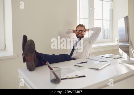 L'uomo d'affari riposa meditando i sogni sul posto di lavoro al tavolo con un computer in ufficio Foto Stock