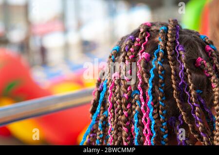 Capelli di ragazza teen con piccole spirali afro con nastri multicolore luminosi Foto Stock