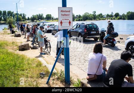 Zons, Germania. 31 maggio 2020. La gente aspetta in una lunga coda al molo dei traghetti per il traghetto Reno da Urdenbach a Zons, mentre un cartello indica le norme sulla distanza. Nel fine settimana di Whitsun, il clima caldo e secco prevale ampiamente in anticipo. Molte persone lo usano per escursioni e attività in natura. Credit: Jonas Güttler/dpa/Alamy Live News Foto Stock