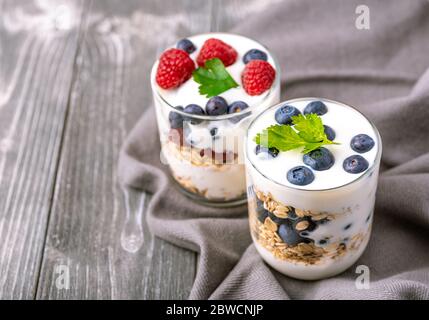 Yogurt bianco in vaso di vetro con mirtilli su sfondo grigio. Foto Stock