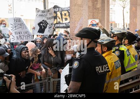 I manifestanti urlano mentre gli ufficiali di polizia si levano tranquillamente contro una protesta 'Not another Black Life' dopo la morte di Regis Korchinski-Paquet a Toronto. Foto Stock