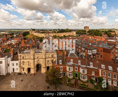 La vista dalla torre della cattedrale di Lincoln mostra la vecchia città di Lincoln, in Inghilterra, con le mura e le torri del castello di Lincoln sullo sfondo. In primo piano si erge il portale gotico Exchequer Gate del XIV secolo. Il castello di Lincoln fu costruito nel 1068 da Guglielmo il Conquistatore su una doppia motta insolita – uno dei soli due castelli di questo tipo in Inghilterra – e ospita ancora una delle quattro copie originali sopravvissute della Magna Carta del 1215. Foto Stock