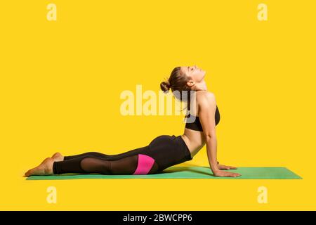 Posa Cobra. Giovane donna in forma in stretto sport che pratica yoga, facendo bhujangasana esercizio sulle mani, allungando i muscoli posteriori per una migliore flessibilità. Foto Stock