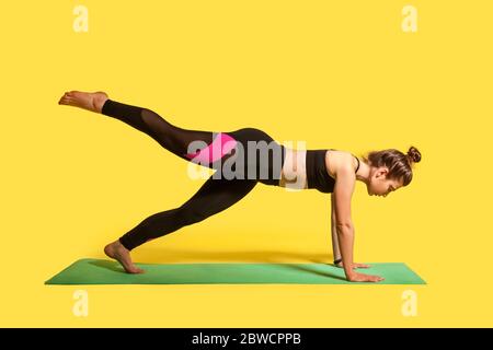 Posa tavola superiore. Giovane donna fitness in stretto sport che pratica yoga, facendo Phalakasana esercizio con gamba sollevamento, muscoli di allenamento. studio shot, s Foto Stock