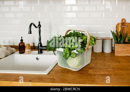 Insalate fresche ed erbe in cesto di metallo sul tavolo in cucina. Concetto di shopping senza sprechi. Vita sostenibile Foto Stock