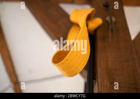 Vista ad angolo ridotto del nastro giallo del carato annodato alla trave in legno Foto Stock