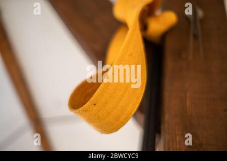 Vista ad angolo ridotto del nastro giallo del carato annodato alla trave in legno Foto Stock