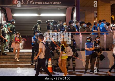 I pedoni passano davanti alla stazione ferroviaria del Principe Edward MTR sotto sorveglianza della polizia durante la commemorazione del decimo mese dopo che centinaia di dimostranti anti anti anti-governo sono stati attaccati da polizia in scontri alla stazione della metropolitana. Foto Stock