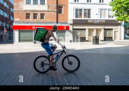 Uber mangia un deliveryman di bicicletta controllando l'indirizzo sul suo smartphone in un Liverpool vuoto Foto Stock