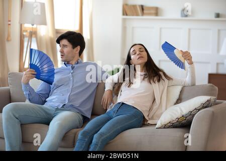 La coppia malva usa la ventola della mano che soffre di tempo caldo Foto Stock