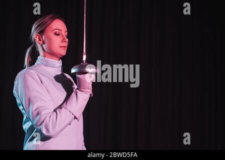 Fencer in tuta da recinzione con pinza isolata su nero Foto Stock