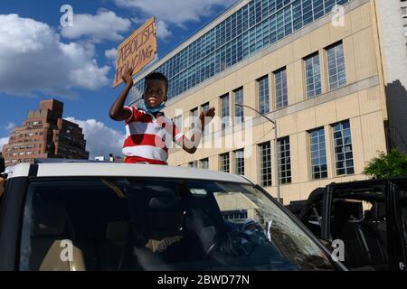 Un bambino si alza attraverso il tetto di una vettura che porta un cartello che dice ' abolire la polizia ' a sostegno della marcia per George Floyd. Foto Stock