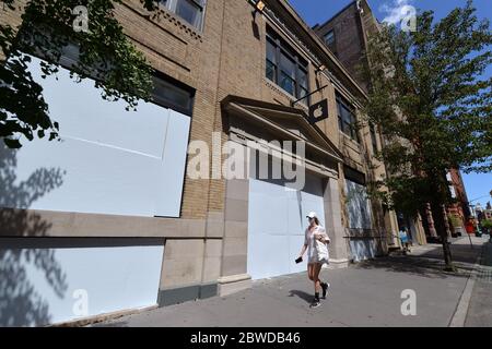 Una donna che indossa una maschera protettiva al tempo di COVID-19, cammina oltre un negozio di Apple imbarcato nella sezione Soho di New York, NY, 31 maggio 2020. I dimostranti che protestavano per l'uccisione di George Floyd hanno danneggiato diverse imprese e hanno frantumato le finestre la notte precedente.(Anthony Behar/Sipa USA) Foto Stock