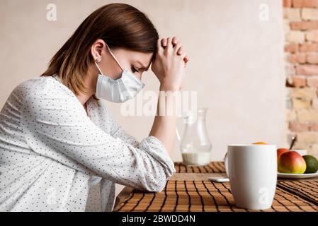 fuoco selettivo della donna incinta in maschera medica con le mani aggrinzite vicino a frutta e bevande Foto Stock