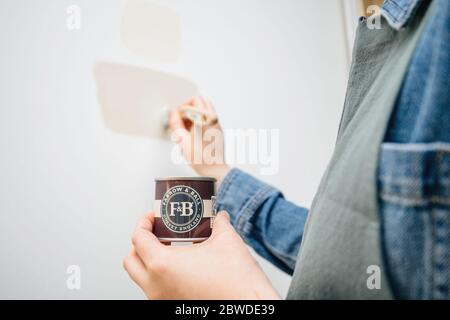 Parigi, Francia - 30 maggio 2020: Pittura donna con Farrow e Ball campione vaso di nuovo colore sulla sua parete durante la ricostruzione dell'appartamento casa Foto Stock