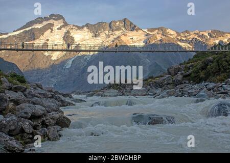 Ponte sospeso sul Hooker Valley Track con il monte Sefton alle spalle Foto Stock