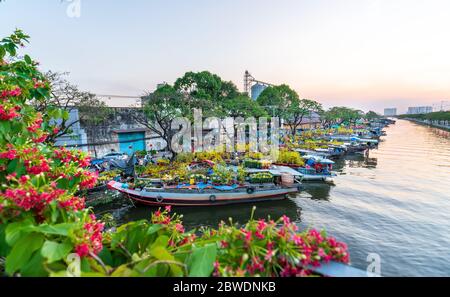 I turisti che si trovano a bordo di un SUP possono ammirare dall'alto il paddleboardon lungo il mercato dei fiori sul fiume nel tardo pomeriggio nella città di ho Chi Minh, in Vietnam Foto Stock