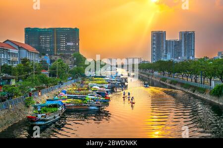 I turisti che si trovano a bordo di un SUP possono ammirare dall'alto il paddleboardon lungo il mercato dei fiori sul fiume nel tardo pomeriggio nella città di ho Chi Minh, in Vietnam Foto Stock