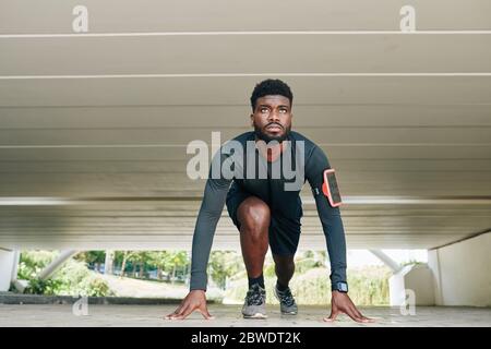 Concentrato giovane velocista di fit sulla linea di partenza della pista pronta per correre Foto Stock