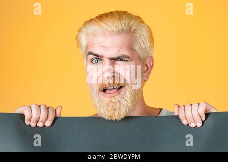 Il giovane mostra un foglio di carta nella fotocamera su uno sfondo a colori. Visualizzazione foglio di disegno opuscolo prima lettura. Foto Stock