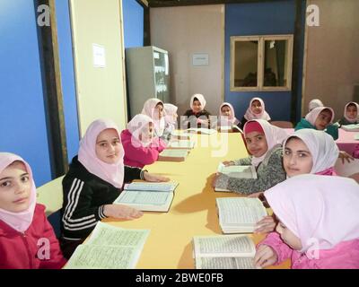 La scuola primaria ragazze che studiano prenota.Una scuola islamica dove le ragazze dovrebbero indossare foulard e sciarpe vestire uniformi Foto Stock