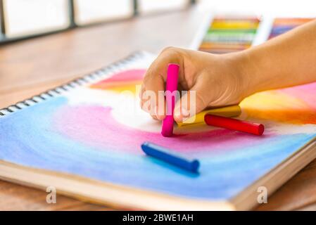 Le ragazze fanno un disegno multicolore con pastello di cera colorato su un pad di schizzo Foto Stock