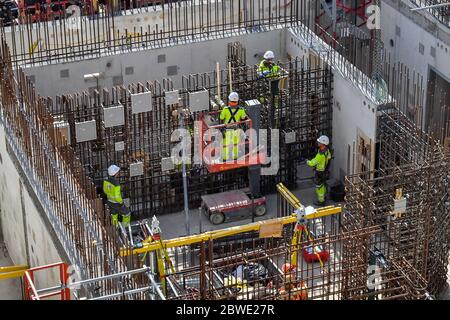 I lavoratori edili restano socialmente distanziati mentre lavorano su rinforzi in acciaio presso la centrale nucleare di Hinkley Point C vicino a Bridgwater, Somerset, il più grande cantiere d'Europa, dove stanno completando un getto di calcestruzzo nella base del reattore nucleare dell'unità 2. Foto Stock