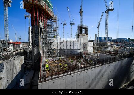 I lavoratori edili restano socialmente distanziati mentre lavorano su rinforzi in acciaio presso la centrale nucleare di Hinkley Point C vicino a Bridgwater, Somerset, il più grande cantiere d'Europa, dove stanno completando un getto di calcestruzzo nella base del reattore nucleare dell'unità 2. Foto Stock