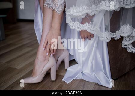 sposa indossa le scarpe da sposa al mattino Foto Stock