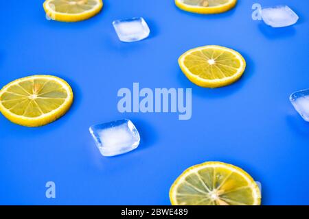 Disposizione della limonata con succulente fette di limone, cubetti di ghiaccio su sfondo blu Foto Stock