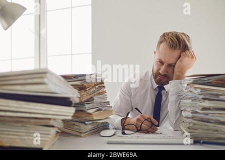 Esausto lavoratore stanco sul posto di lavoro ha coperto il suo volto con le mani in ufficio Foto Stock