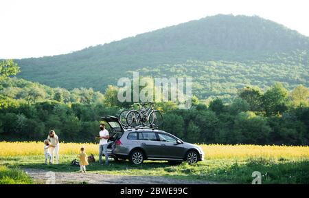 Famiglia con due bambini piccoli e maschere di protezione in viaggio in bicicletta in campagna. Foto Stock